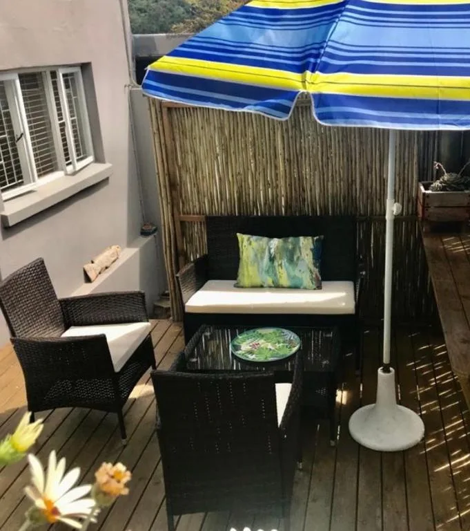 Outdoor patio with blue umbrella, black furniture and wooden decking area