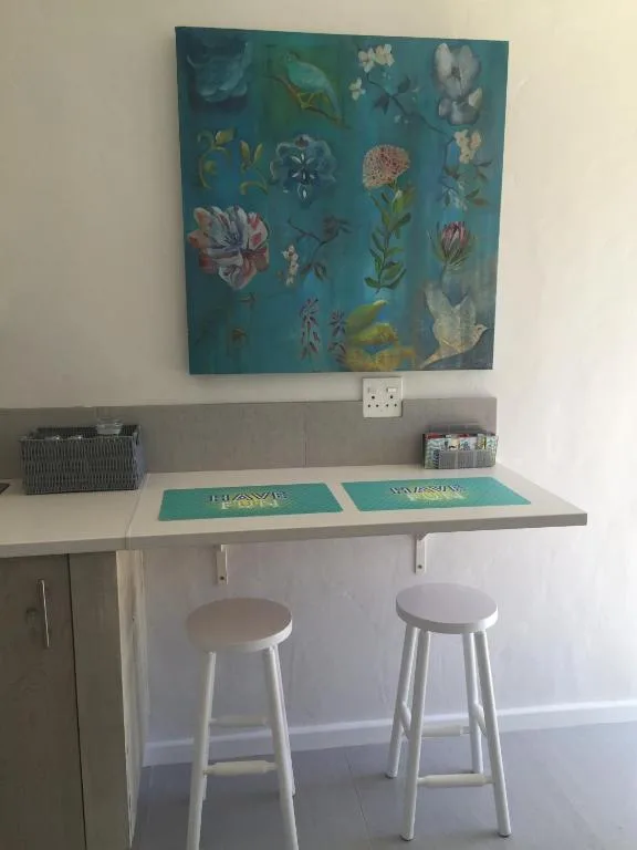 Workspace with floral wall art, desk, and white bar stools
