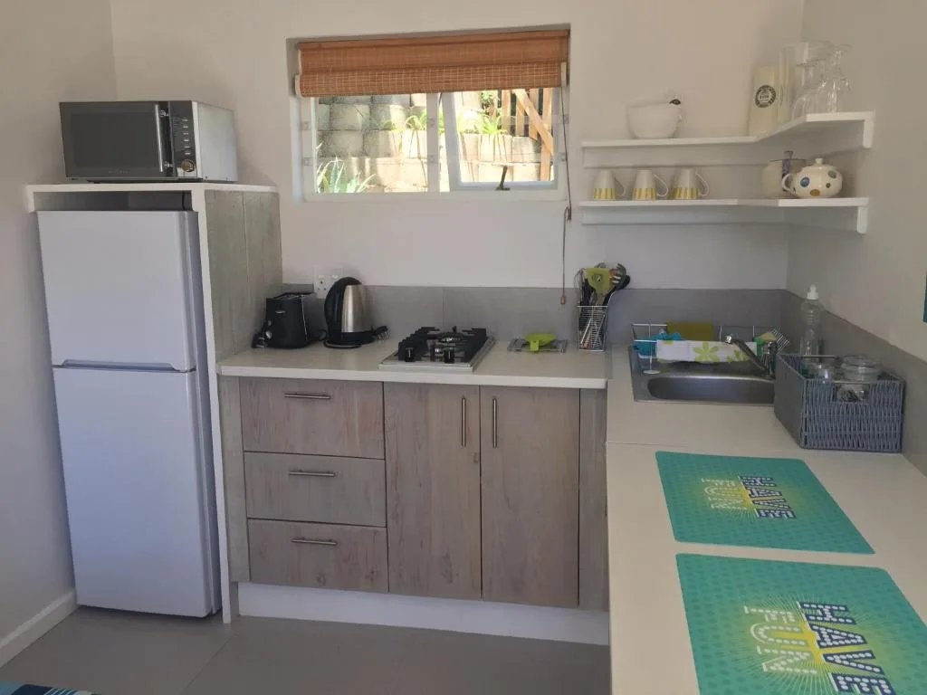 Compact kitchenette with white fridge, gas cooktop, and open shelving