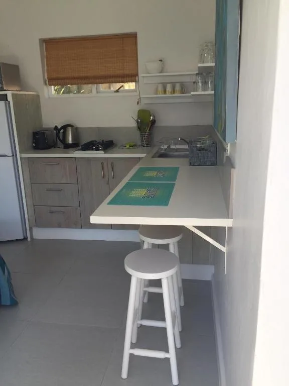 Modern kitchenette with counter seating, stainless steel appliances, and storage