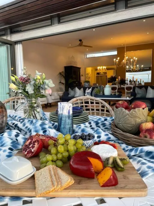 Dining table with fresh fruit and vegetables, open-plan lounge visible beyond