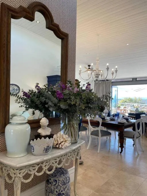 Elegant lounge with decorative mirror, fresh flowers, and coastal views