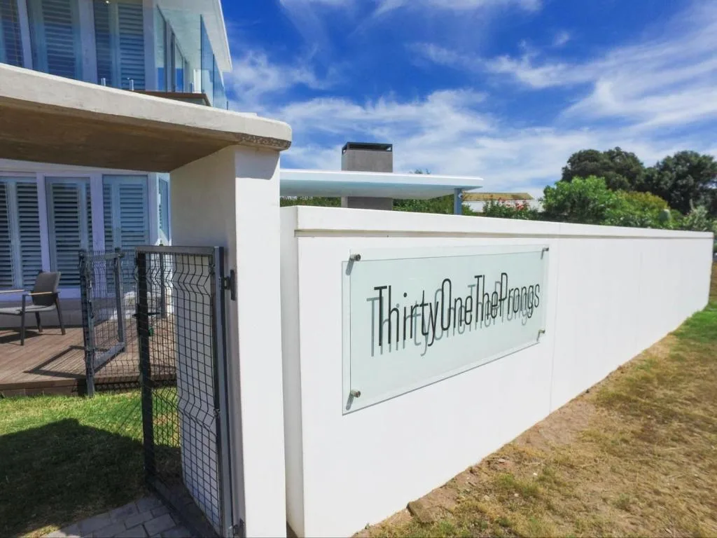 Modern white property entrance with signage and gated access to garden area