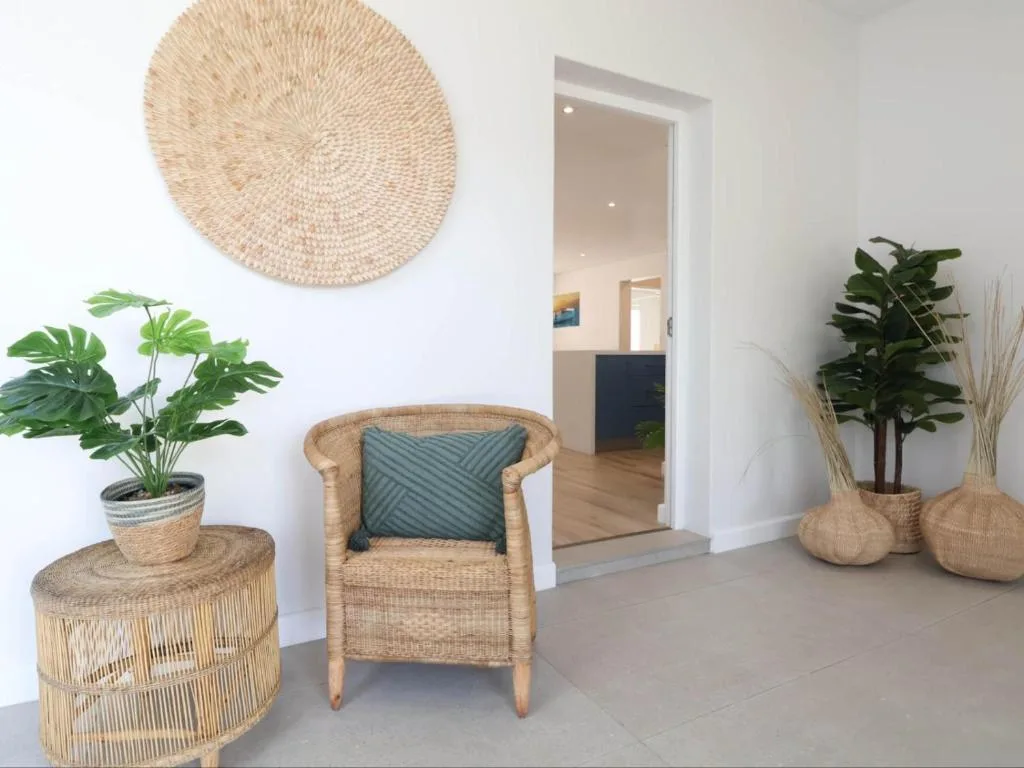 Bright lounge space with woven chair, plants, and decorative basket wall art