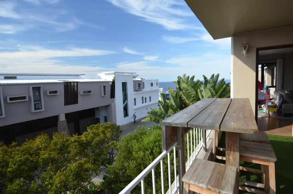 Wooden deck with sea view overlooking modern white apartments and coastal landscape