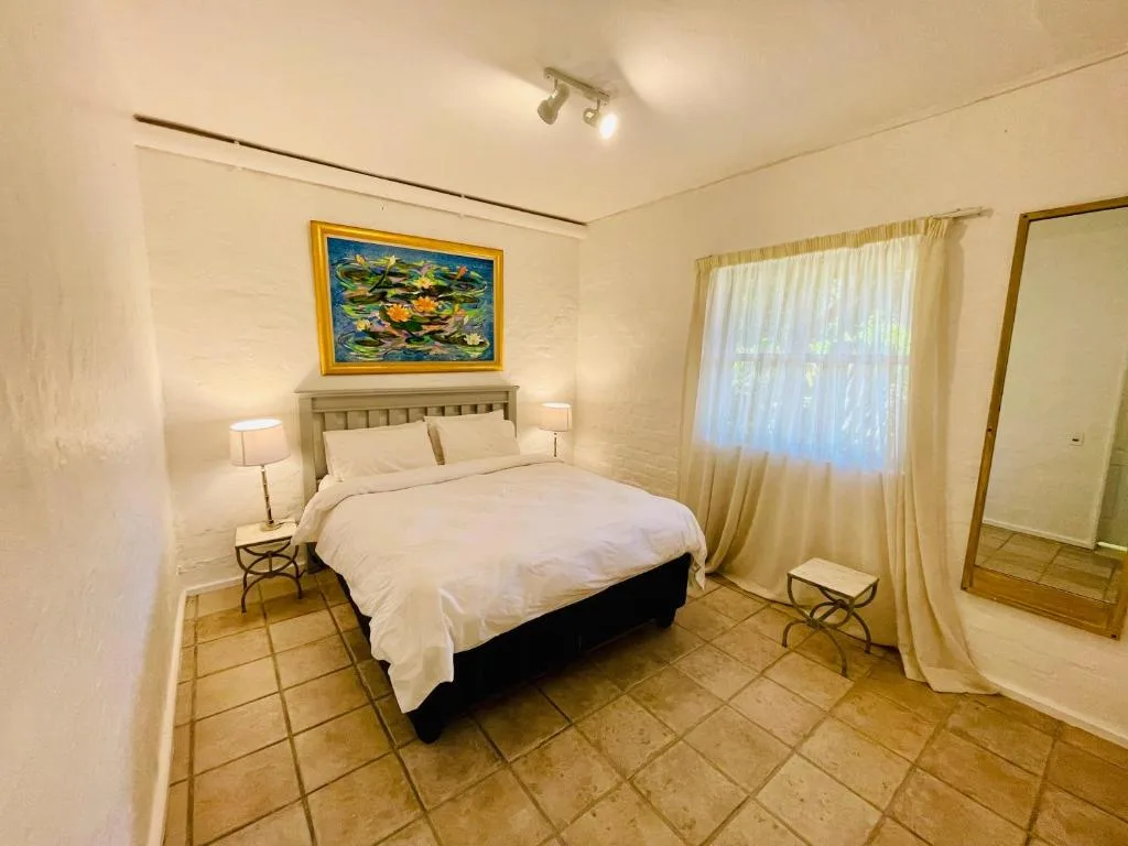Bright bedroom with queen bed, white linens, and large windows with sheer curtains