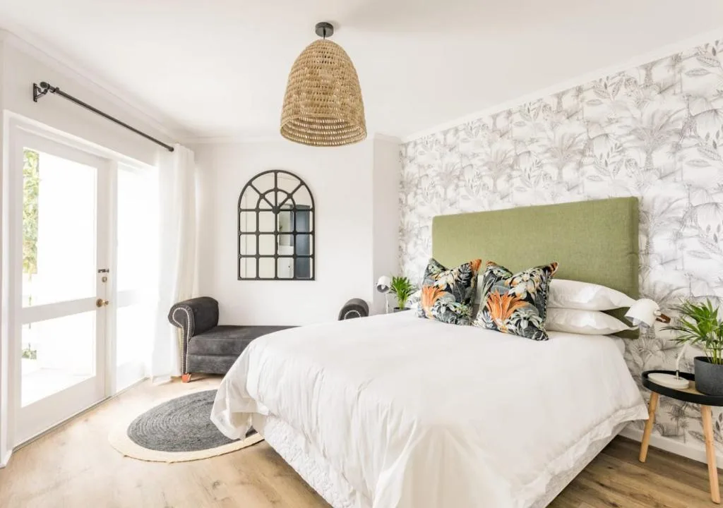 Bright bedroom with green upholstered headboard and botanical wallpaper