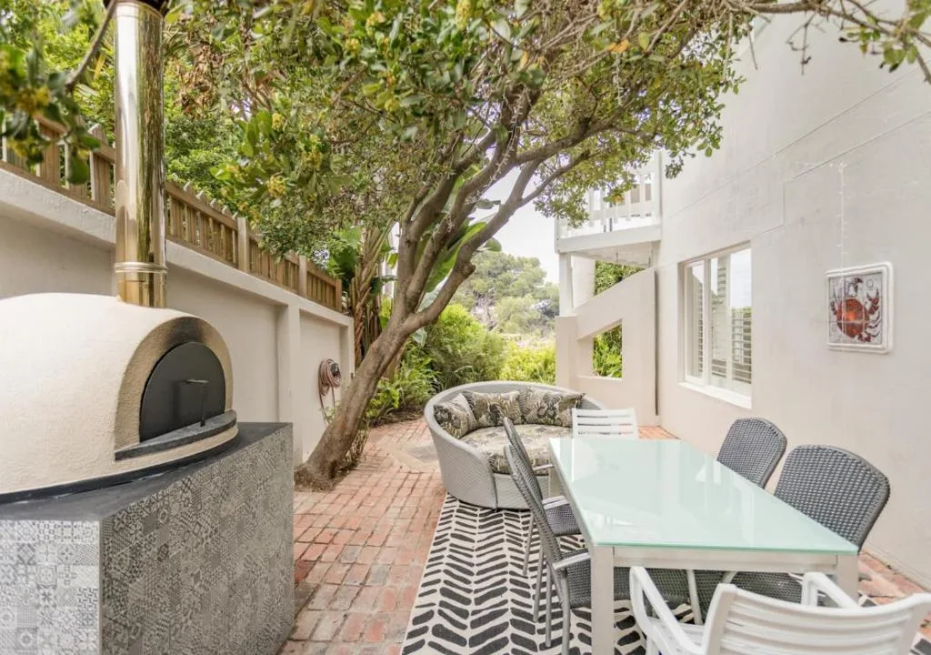 Outdoor patio with dining table, pizza oven, and shaded seating area