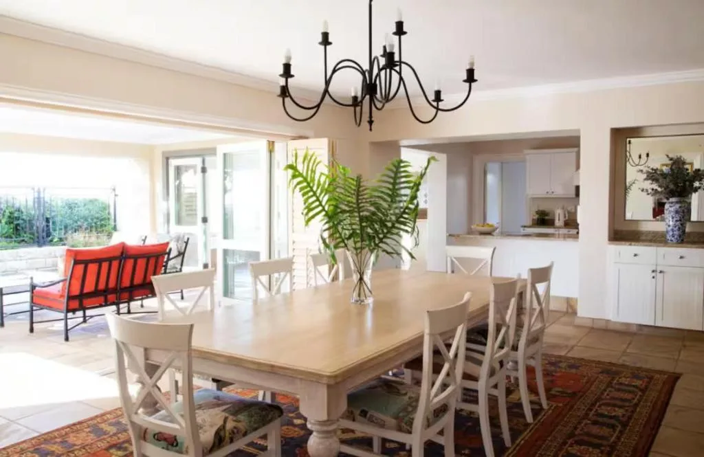 Spacious dining room with cream table, x-back chairs, elegant chandelier overhead
