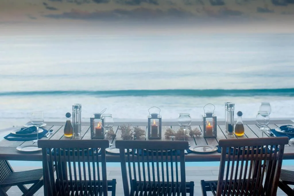 Ocean-view dining deck with place settings and lanterns overlooking beach