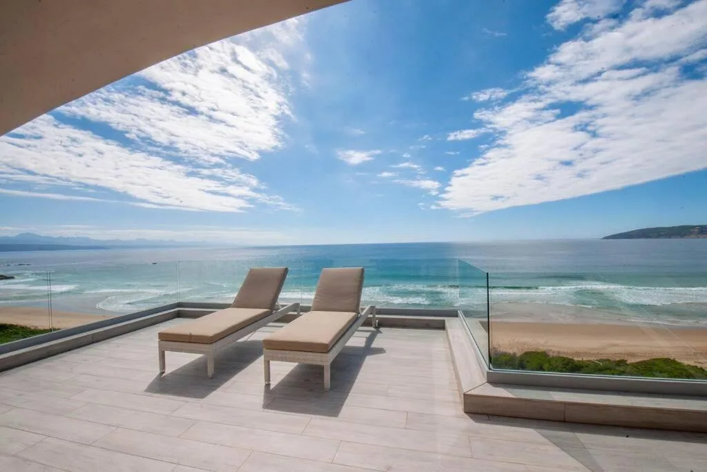 Beachfront deck with loungers overlooking pristine ocean and sandy beach