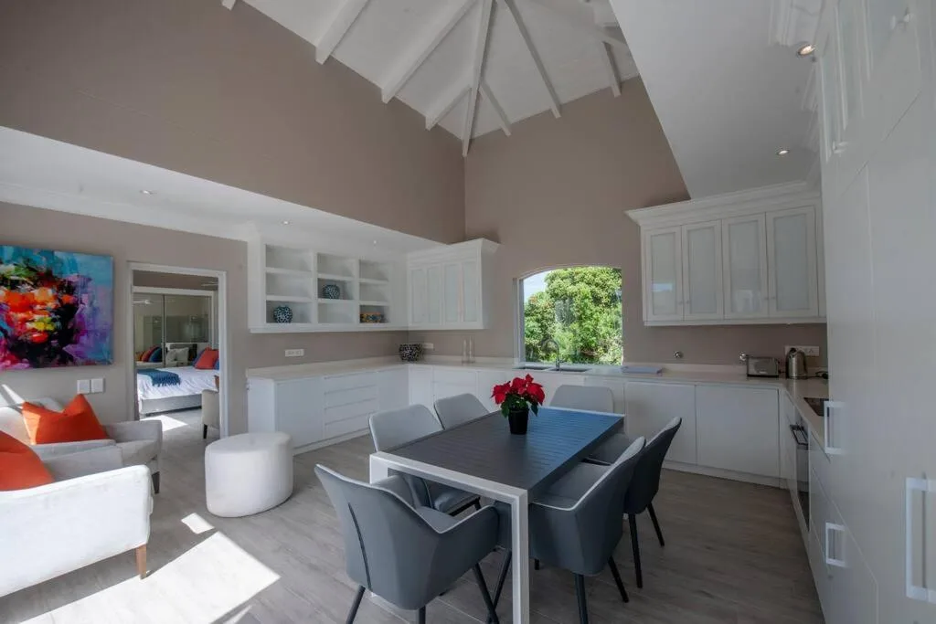 Modern dining area with black table, gray chairs, and open-plan kitchen