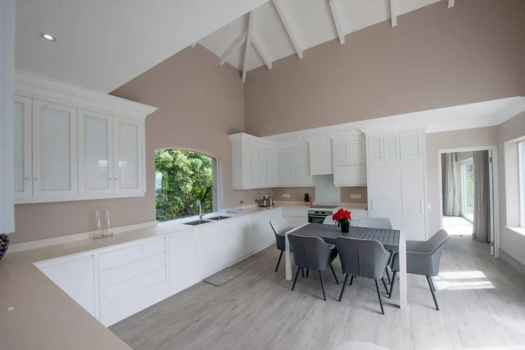 Modern open-plan kitchen with white cabinetry, dining table, and vaulted ceiling