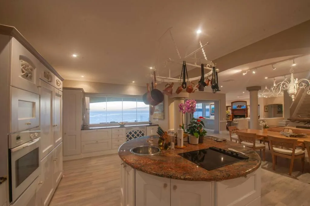 Modern kitchen with granite island, white cabinetry, ocean view windows