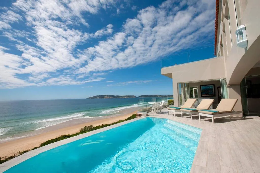 Infinity pool overlooking pristine beach and ocean with loungers beyond