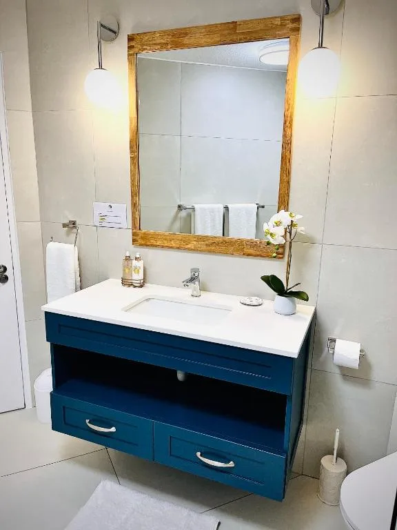 Modern bathroom with blue vanity, white sink, and wooden-framed mirror