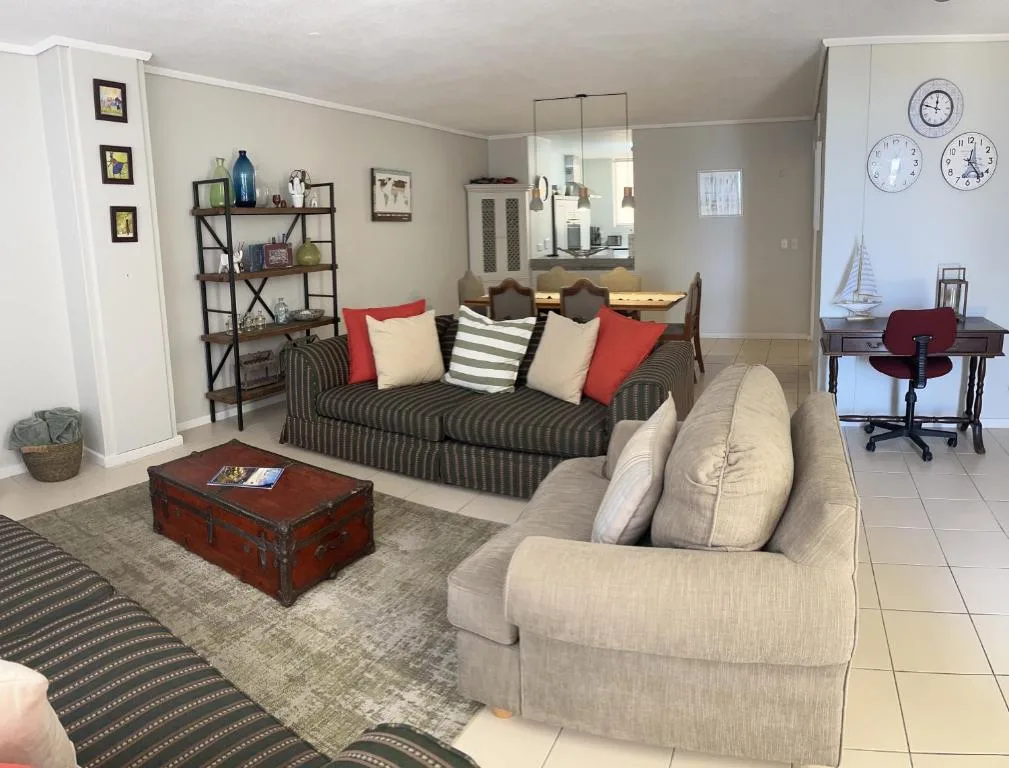 Open-plan lounge with striped sofa, cream armchair, and dining area visible