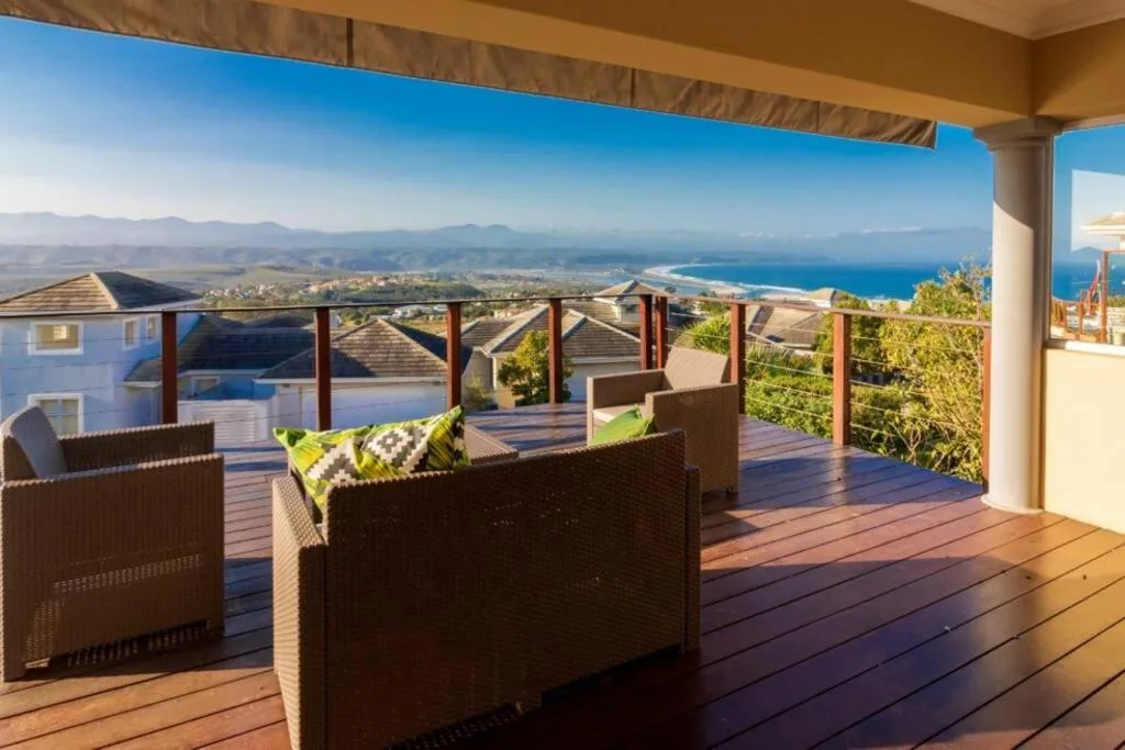 Wooden deck with wicker seating overlooking coastal town and ocean views