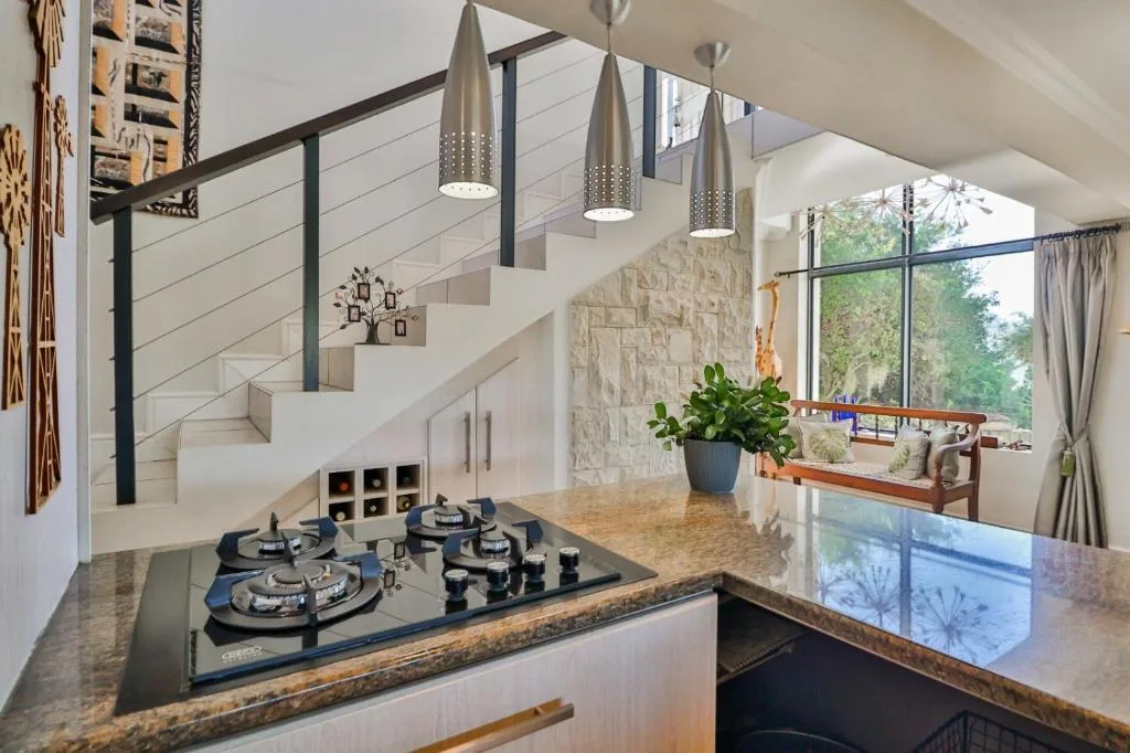 Modern kitchen with gas cooktop, granite counters, pendant lights, and open plan living space
