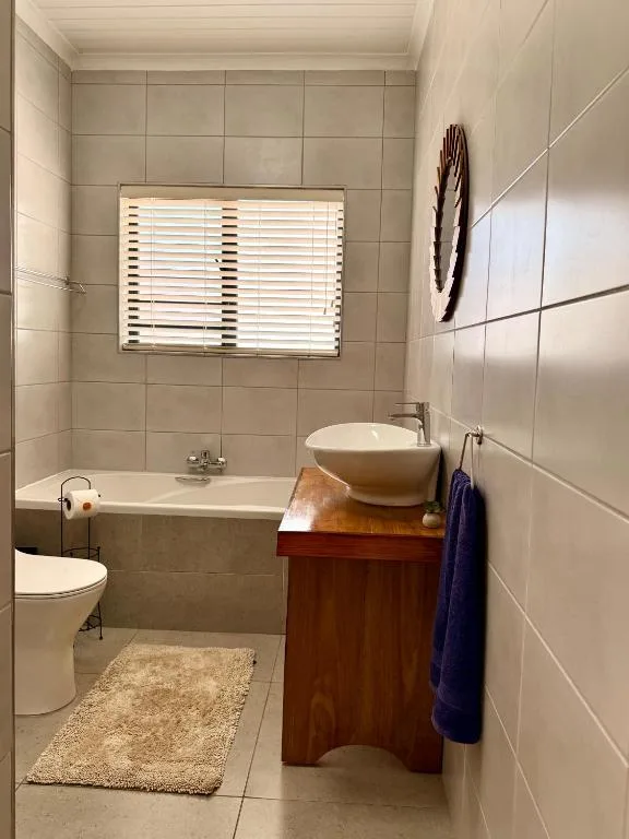 Modern bathroom with tiled walls, vessel sink, bathtub, and toilet