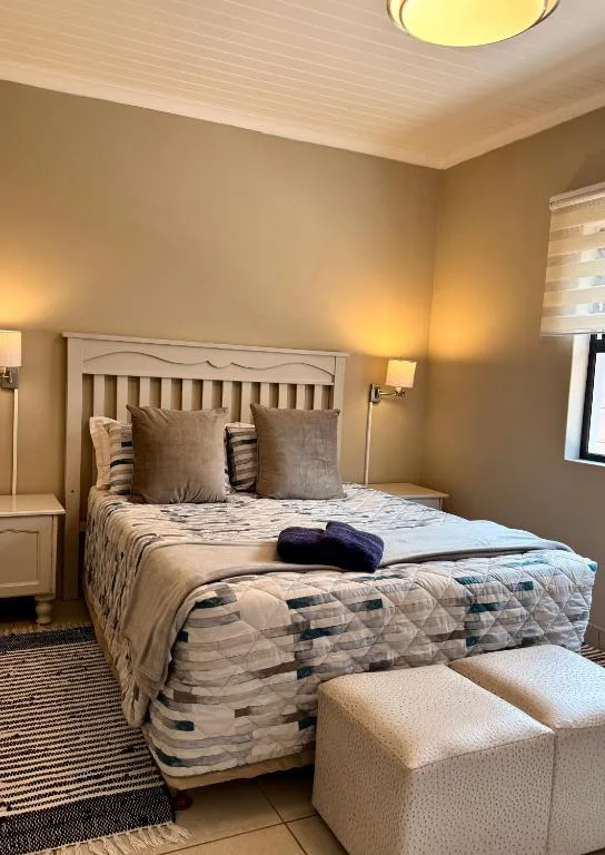 Warm bedroom with queen bed, neutral bedding, and upholstered seating