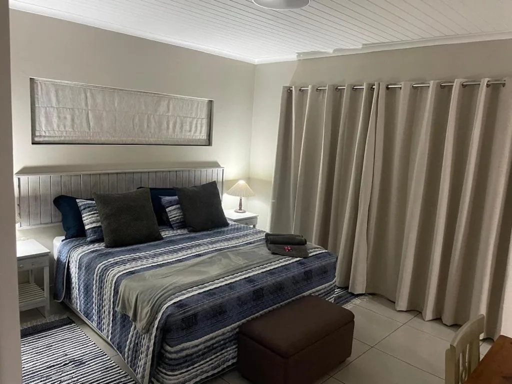 Modern bedroom with striped bedding, blue pillows, and neutral curtains