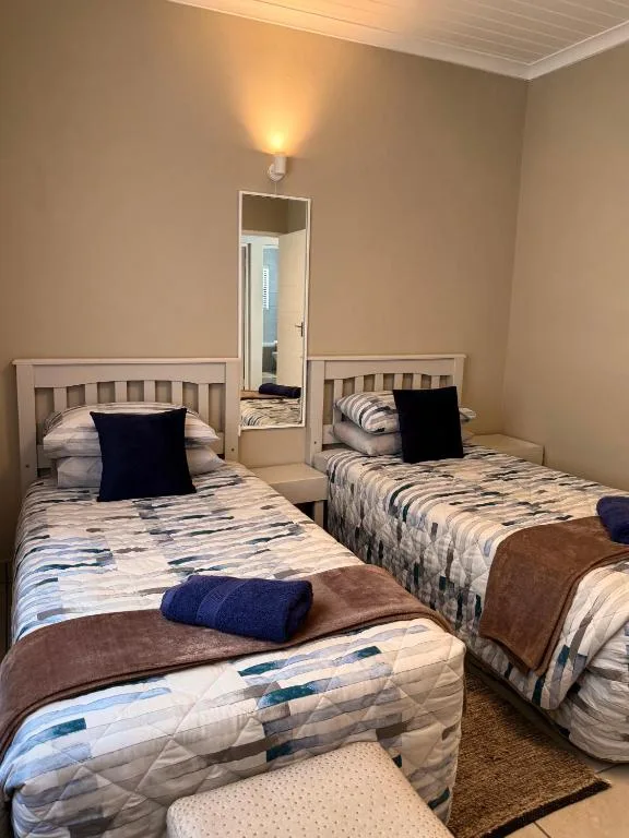 Twin bedroom with striped bedding, navy pillows, and mirror between beds