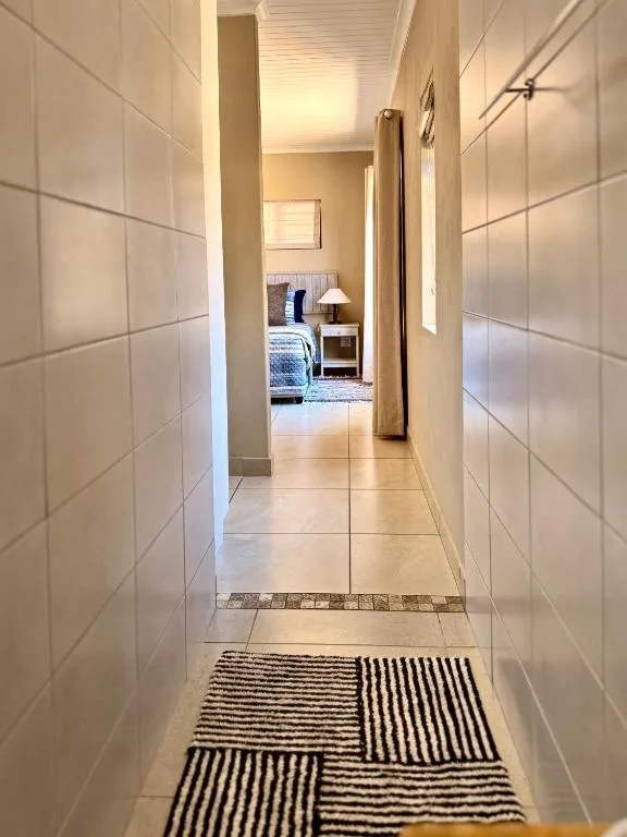 Modern hallway with tiled walls and striped runner mat leading to bedroom