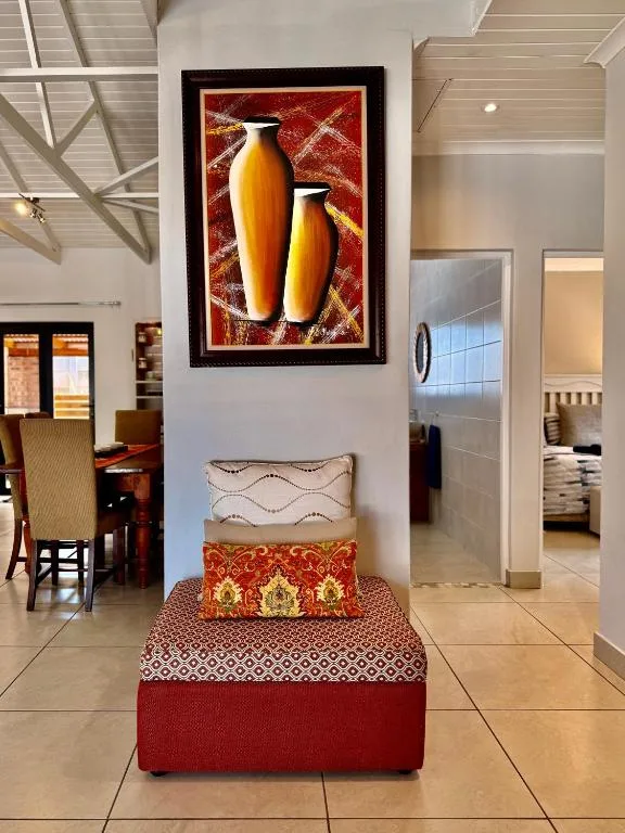 Decorative cushioned ottoman with colorful patterned pillows and framed artwork