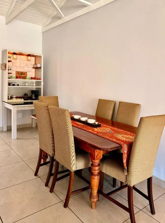 Wooden dining table with four beige upholstered chairs and coffee station