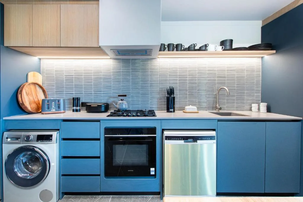 Modern kitchen with blue cabinetry, gas stove, oven, and integrated appliances