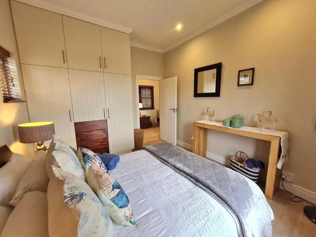 Bright bedroom with double bed, built-in wardrobes, and wooden dresser