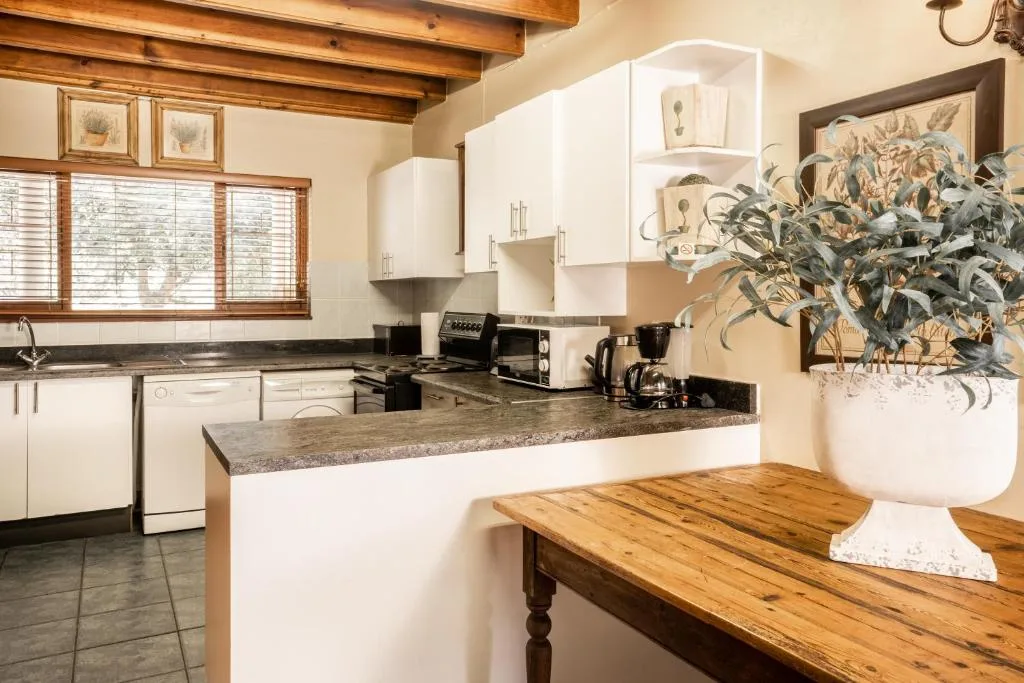 Modern kitchen with white cabinetry, granite countertop, and wooden beam ceiling