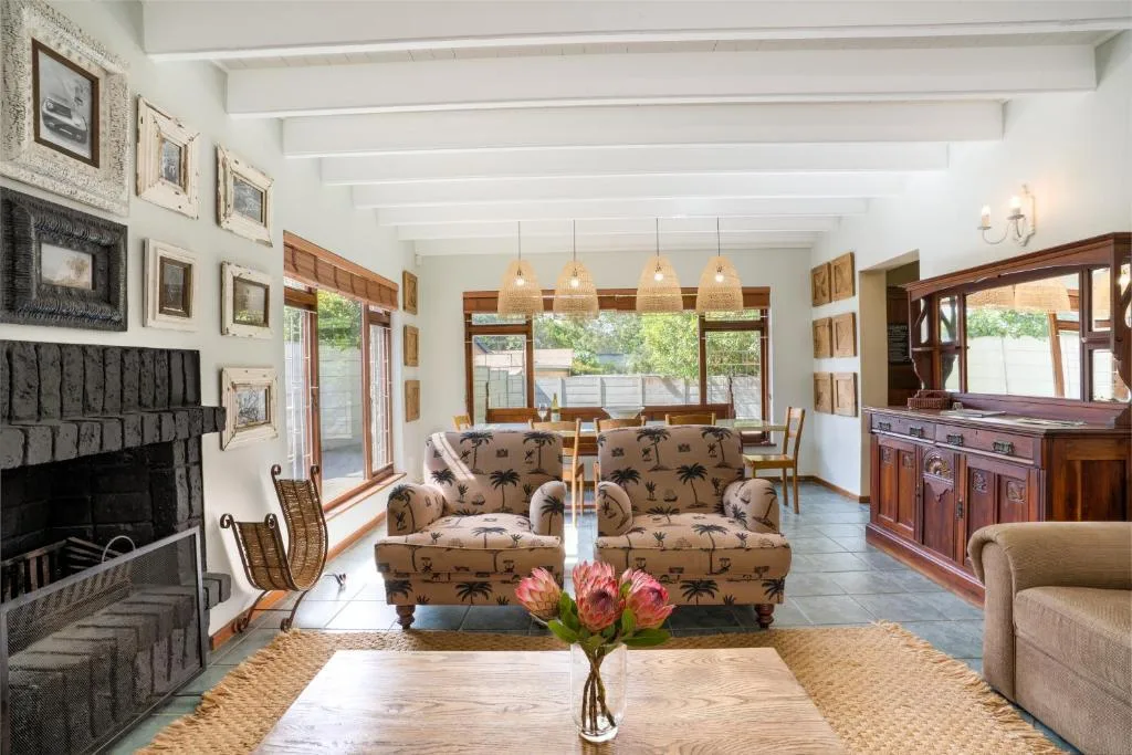 Spacious lounge with patterned armchairs, fireplace, and large windows overlooking garden