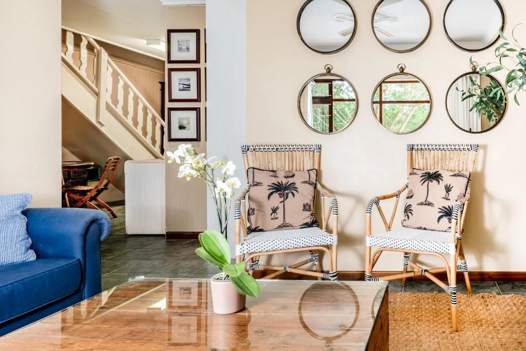 Bright living room with blue sofa, rattan chairs, and decorative mirrors