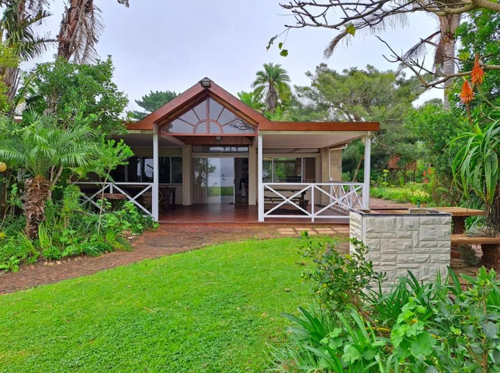 Modern cottage with wooden deck surrounded by lush gardens and mature trees