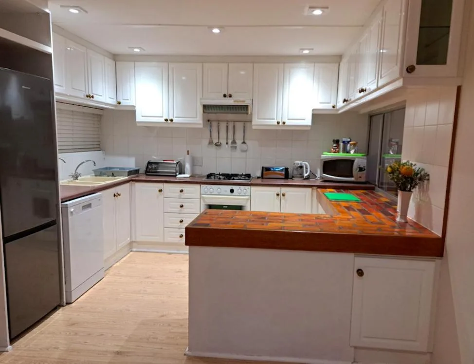Modern kitchen with white cabinetry, wooden island countertop, and stainless steel appliances