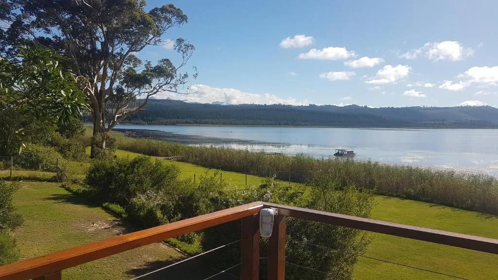 Scenic lake view with mountains, native trees, and lush green gardens