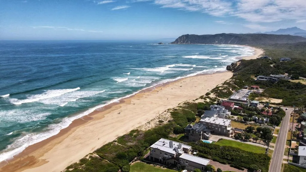 Aerial view of pristine sandy beach with rolling waves and coastal headland