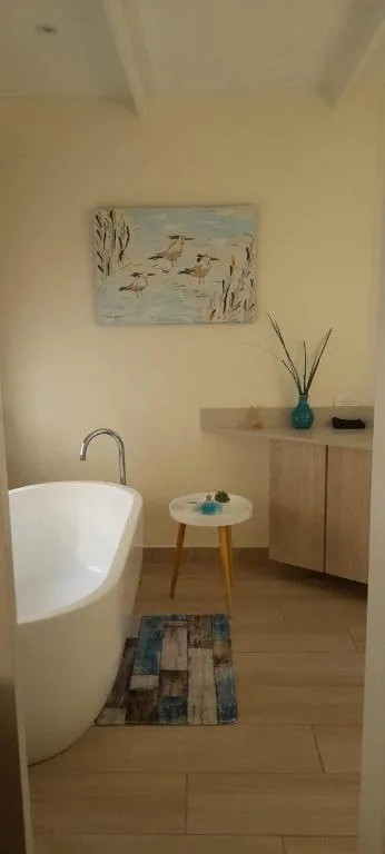 Modern freestanding bathtub with decorative accessories and artwork in bright bathroom