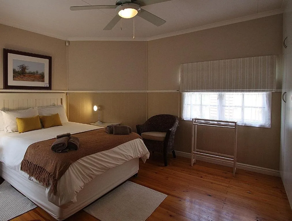 Spacious bedroom with queen bed, wooden floors, and ceiling fan