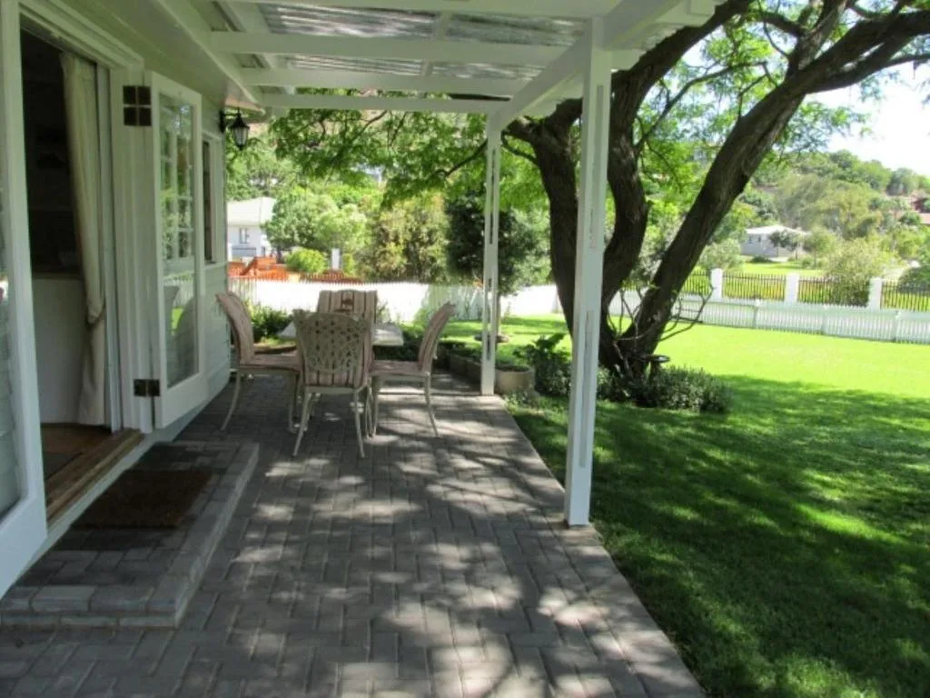 Covered patio with dining table, mature tree, lush green lawn views