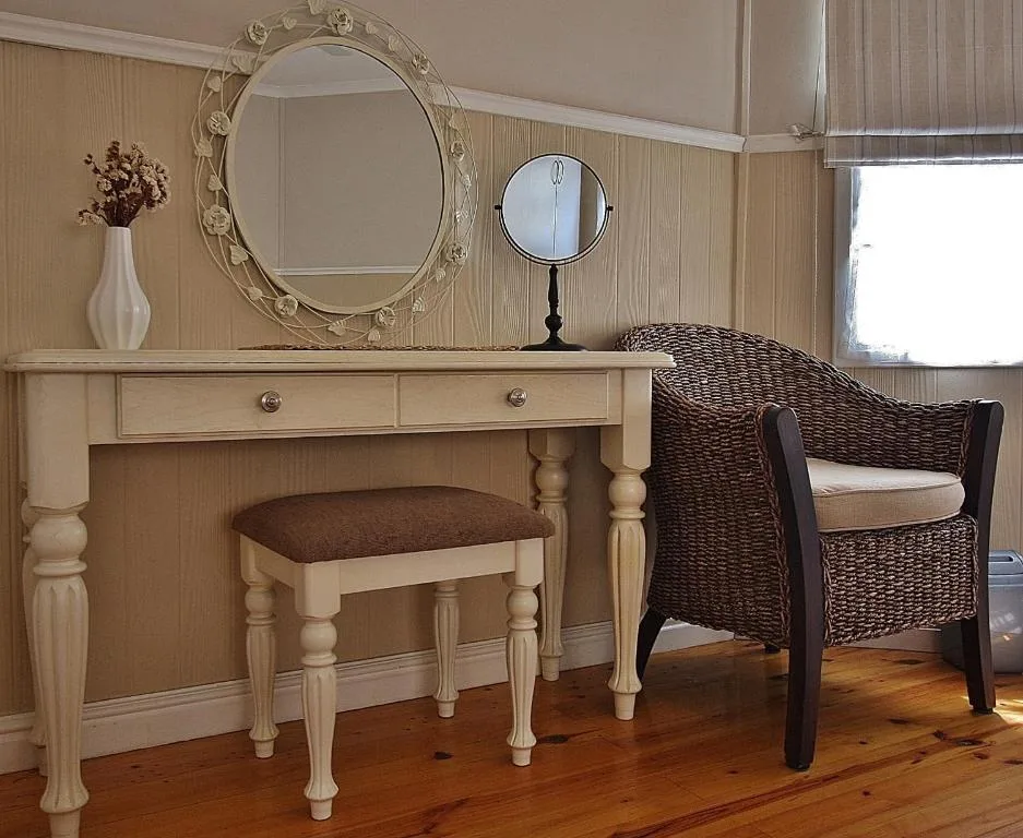 Elegant cream vanity with ornate mirror, wicker chair, and decorative accessories