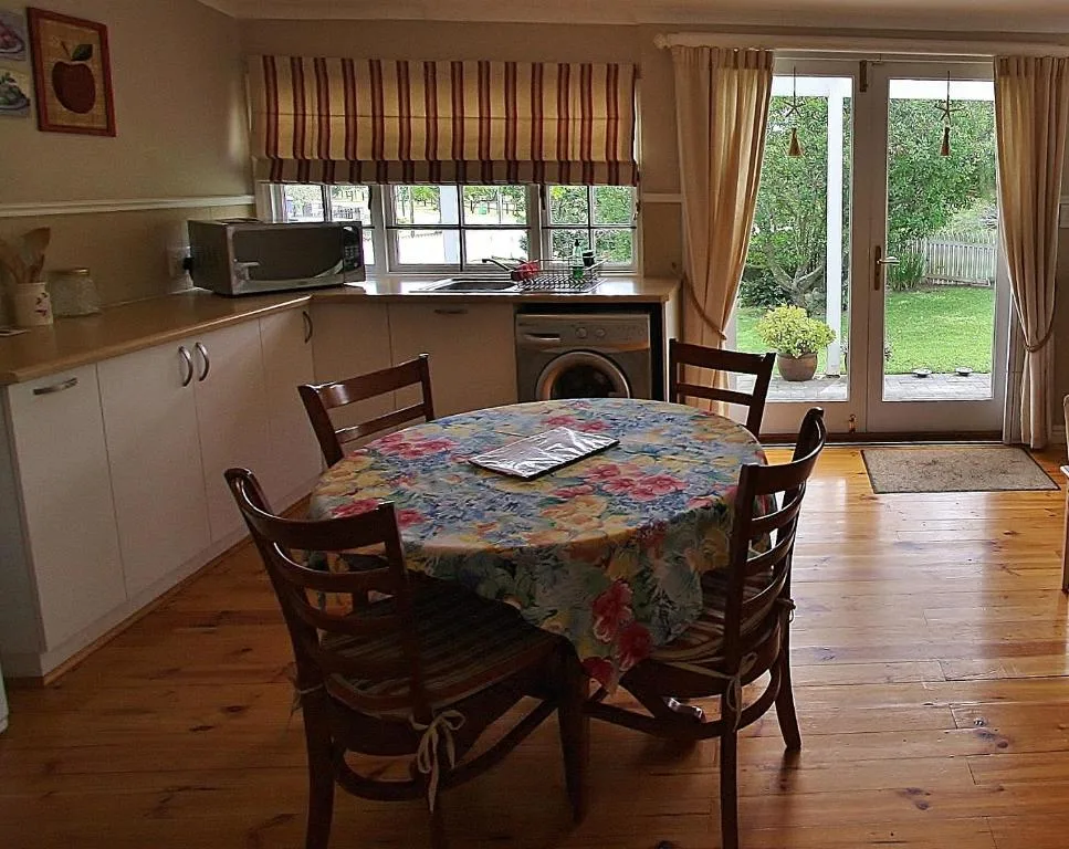 Dining table with floral tablecloth and wooden chairs in open-plan kitchen area