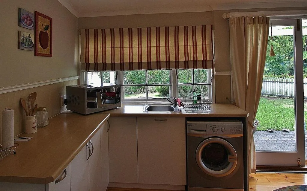 Bright kitchen with washing machine, microwave, and garden view through glass doors