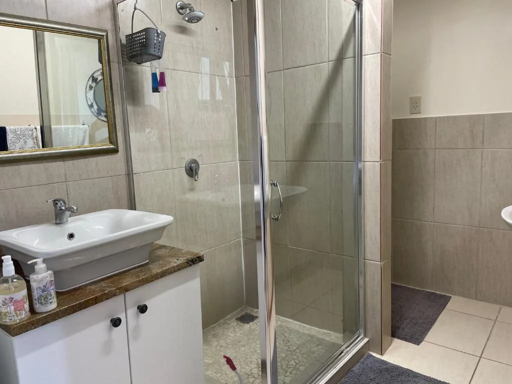 Modern bathroom with vanity sink, glass shower enclosure, and tiled walls