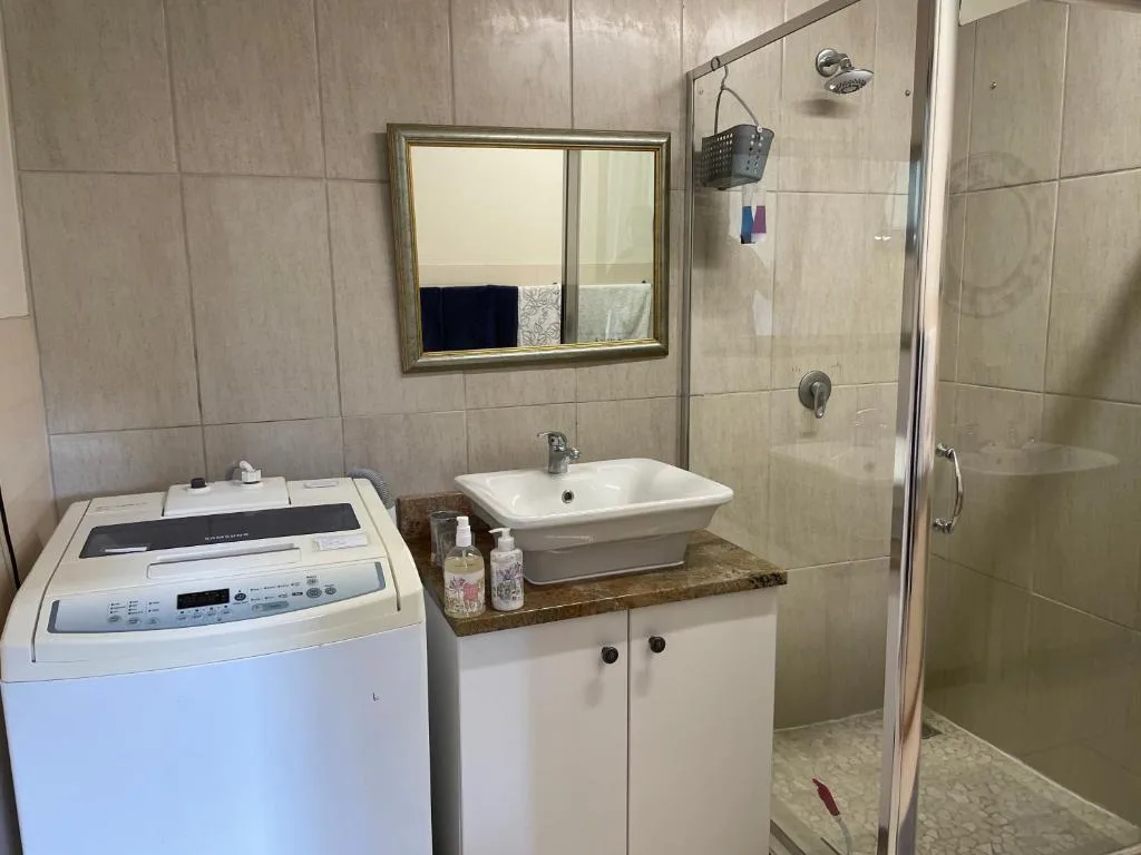 Modern bathroom with vanity sink, washing machine, and shower enclosure