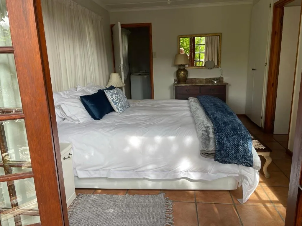 Bright bedroom with queen bed, white linens, wooden frame, and garden views