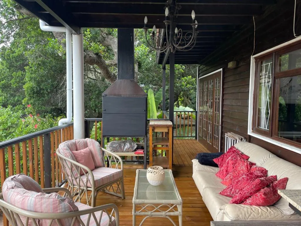 Covered wooden deck with comfortable seating, fireplace, and lush garden views