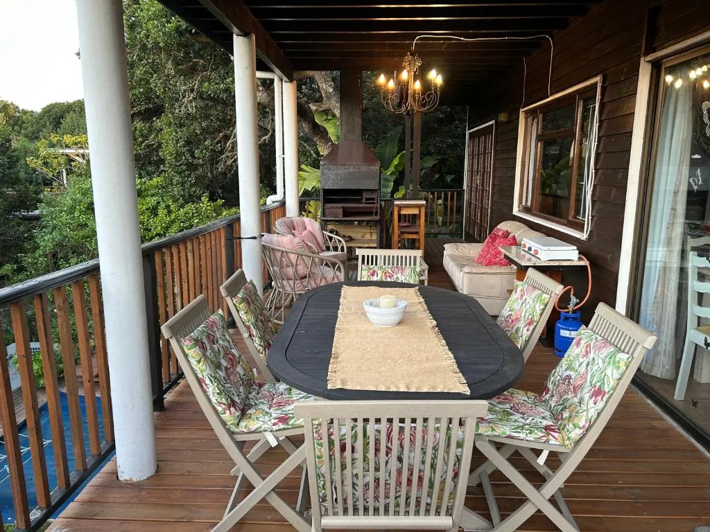 Covered wooden deck with dining table, chairs, and outdoor seating area